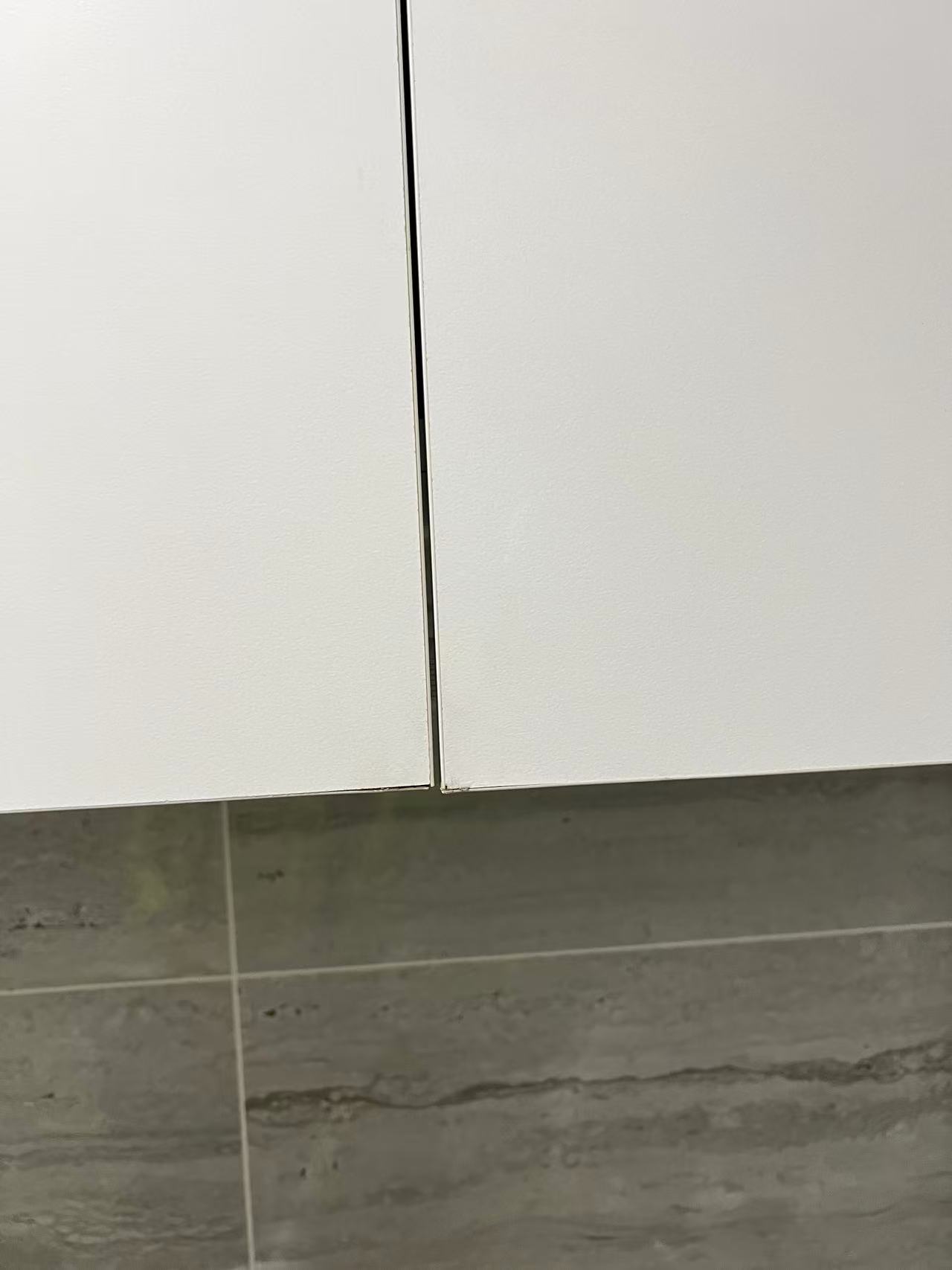 Closed white cupboard doors showing the centre gap and lower corners