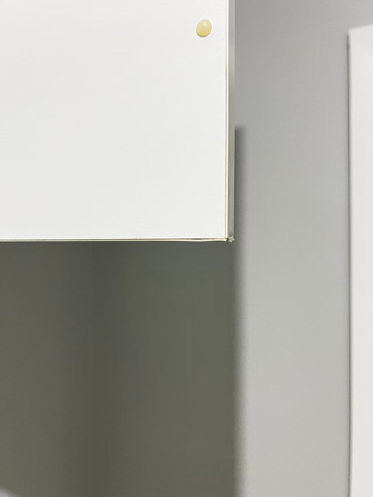 Inside corner of a white cupboard door showing the edge and bumper