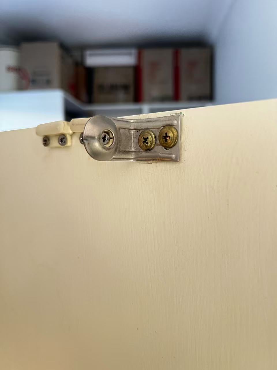 Metal fixing bracket and screws at the top of a white panel