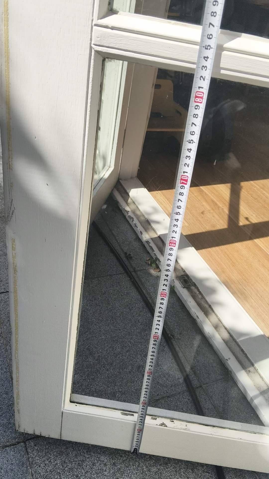 Lower glazed door and threshold beside a tape measure