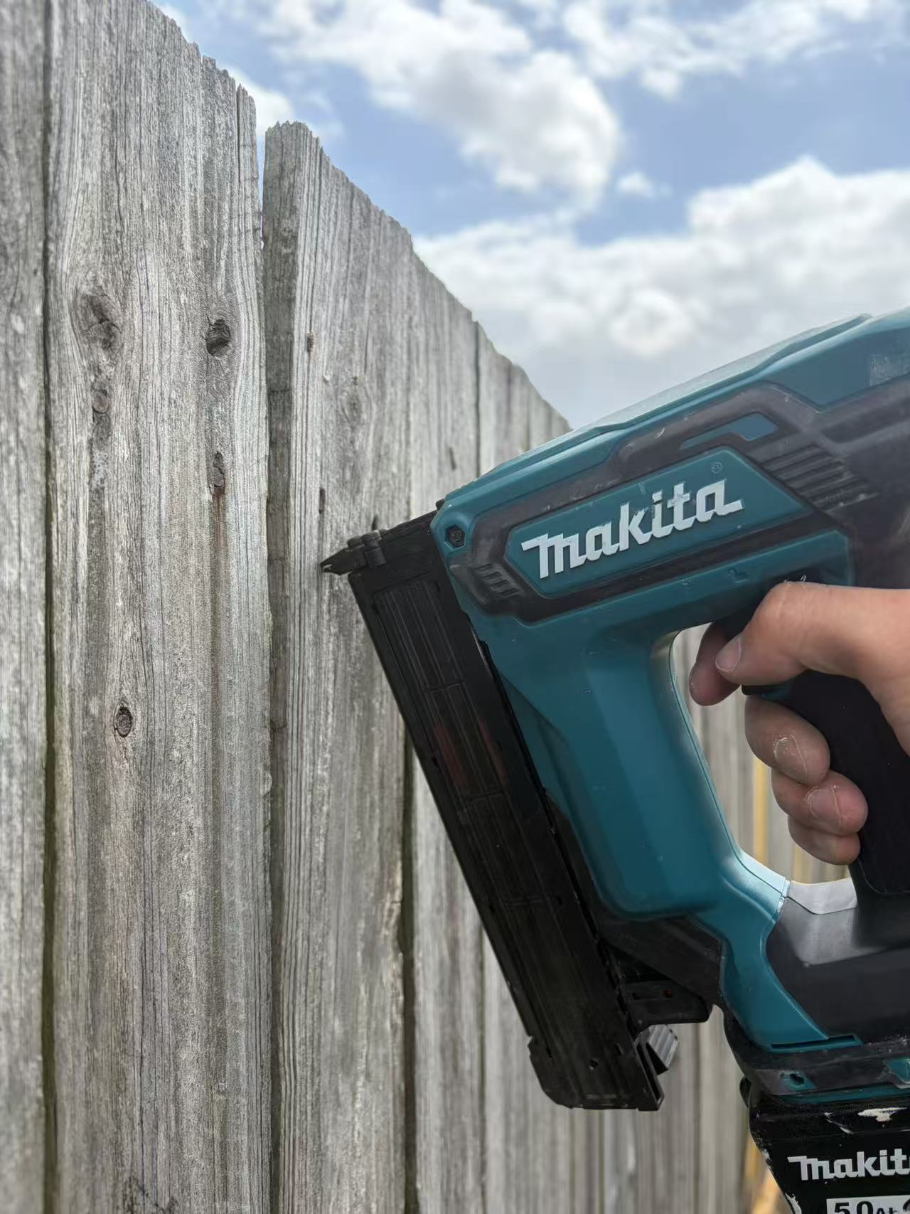 Nail gun held against timber fence boards during work