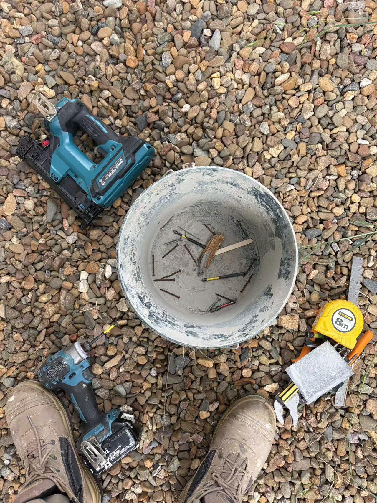 Tools, tape measure and loose fixings on gravel at the work area